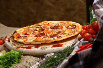 Pizza with mushrooms, tomato, smoked sausage, bacon, red pepper and cheese close-up