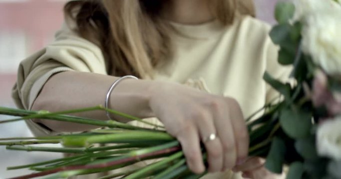 Young Florist Assembles a Rustic Wedding Bouquet. Young florist assembles a perfect wedding bouquet.  She's happy to have small business