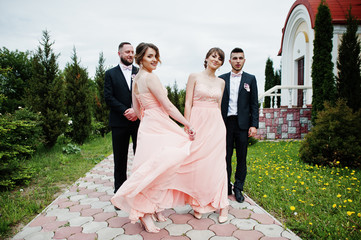 Groomsmen and bridesmaids posing outdoors next to the church.