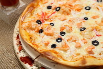 pizza thin olive shrimp crabs on a wooden stand 