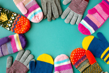 Mittens and gloves of different colors. View from above. Clothes for cold autumn and winter in the form of mittens and gloves. Warm clothing on a turquoise background.