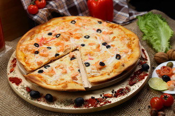 pizza thin olive shrimp crabs on a wooden stand 