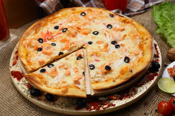pizza thin olive shrimp crabs on a wooden stand 