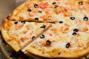 pizza thin olive shrimp crabs on a wooden stand 