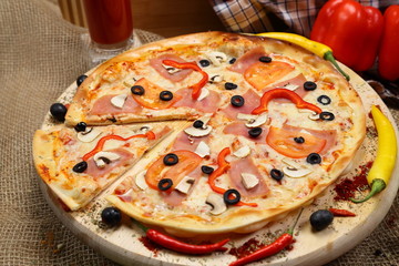 pizza thin olives sausage mushrooms pepper on a wooden stand