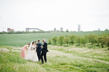 Groomsmen with bridesmaids and wedding couple walking on the flower field.