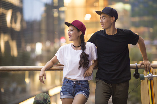 Cheerful young Chinese couple with skateboard dating