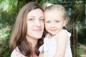 mother and child girl daughter with blue eyes in garden