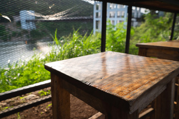 Fototapeta premium Wood desk chair table top with blurry nature suspension bridge background.