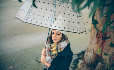 Portrait of young beautiful girl under a umbrella in an autumn rainy day