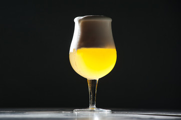 Glass beer with foam on black background with copyspace
