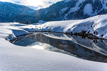 Sun shines in mountain lake in snow-covered landscape in Hohe Tauern Austria