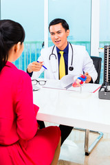 Asian doctor giving patient medical advice in practice or office