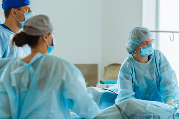 Surgeons team looks at monitors while preforming operation in hospital operating theater, male...