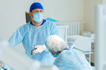 Male surgeon preforming operation uterus removal in hospital operating theater, man surgeon operating patient working with surgical laparoscopy instruments. Gynecology.