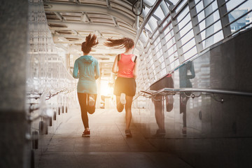 Beautiful two woman running over bridge during sunset.