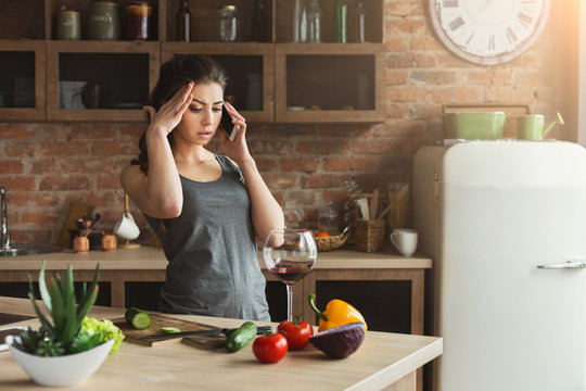 Worried woman talking on phone in home kitchen