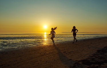 Fototapeta na wymiar two girl running by the sea on the beach