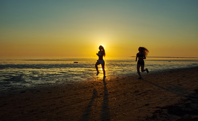 Fototapeta na wymiar two girl running by the sea on the beach
