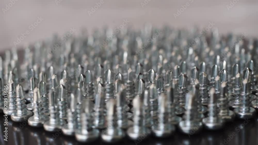 Poster Macro screws rotating on a metal table and black background. Seamless loop.