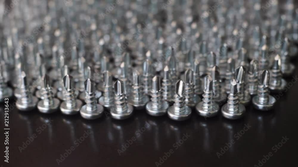 Aufkleber Macro screws rotating on a metal table and black background. Seamless loop.