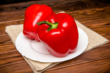 Two red peppers lying on a linen tablecloth 