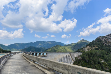 Curved dam path & mountains under clouds