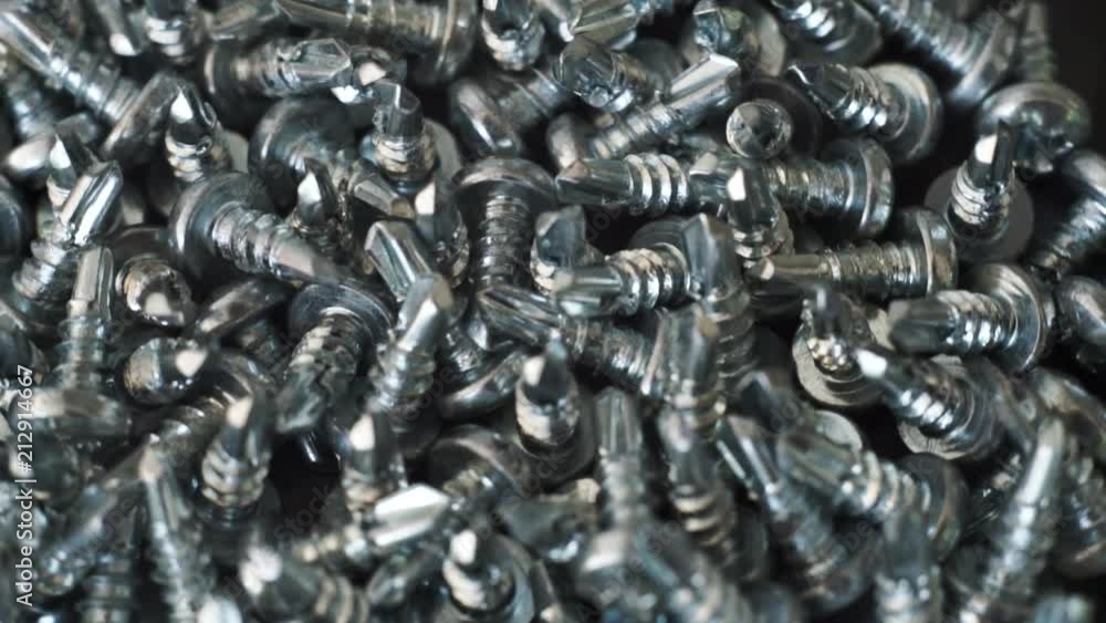 Aufkleber Macro screws rotating on a metal table and black background. Seamless loop.