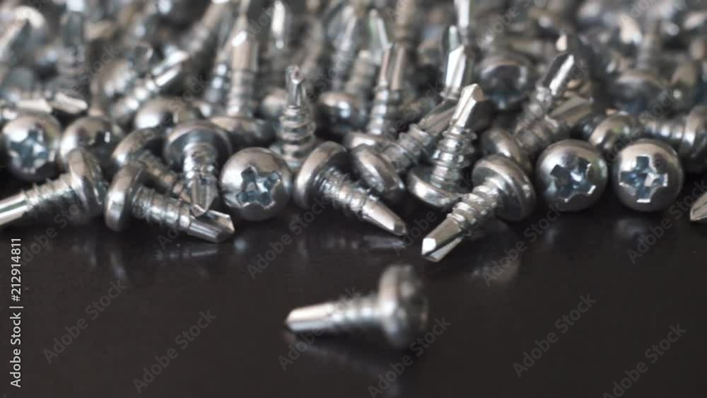 Poster Macro screws rotating on a metal table and black background. Seamless loop.