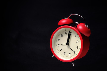 Red vintage alarm clock floating in the dark with blackboard background