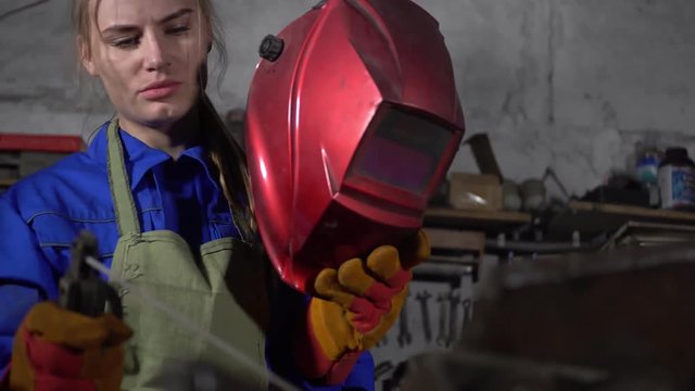 cute welder girl in uniform in the garage working with welding equipment. Women's work in art