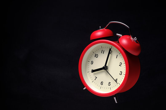Red vintage alarm clock floating in the dark with blackboard background
