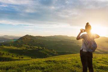 Woman taking photo on mobile phone at the mountain peak.