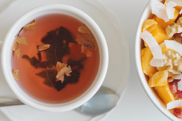 Green tea with hibiscus and rose petals served with a bowl with fresh fruit salad. Healthy vegan breakfast
