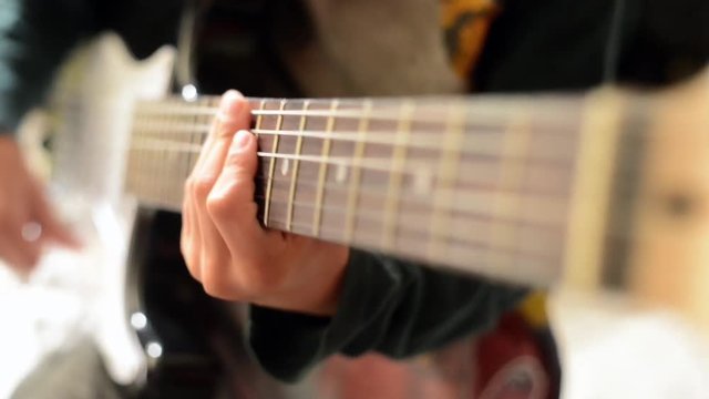 A boy playing the electric guitar close up, finger on the instrument