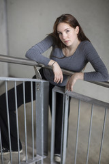 Portrait of a girl standing in a building staircase and smiling sweetly. High angle view. Full length.