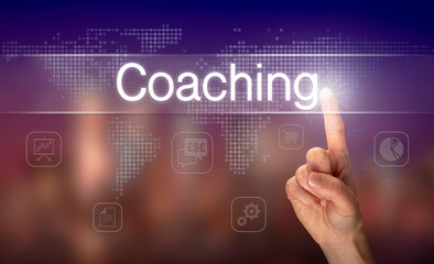 A hand selecting a Coaching business concept on a clear screen with a colorful blurred background.