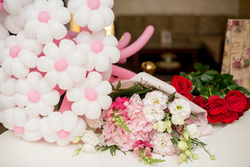 flowers eustoma and rose. A balloon in the form of flowers on a white table