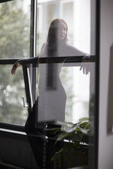 Attractive Female Standing Between Window Glass With Head Turned