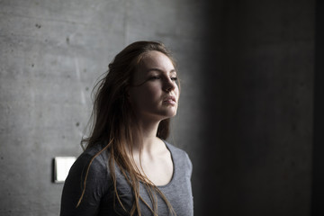 Angled View of Female Model Behind Grey Concrete Wall