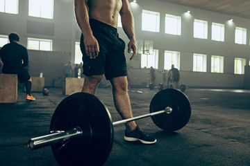 Fit young man lifting barbells working out in a gym