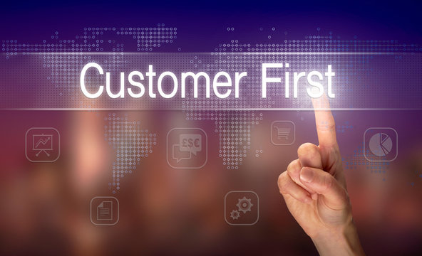 A hand selecting a Customer First business concept on a clear screen with a colorful blurred background.
