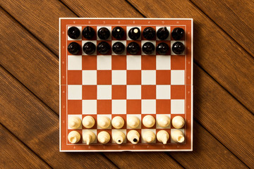 Black and white chess on a chessboard on a wooden table. The view from the top. Chess game concept