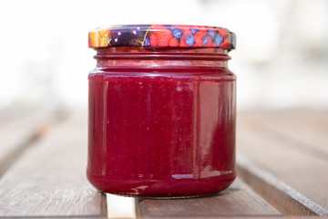 Ein Glas selbstgemachter Erdbeergelee auf einem Holztisch