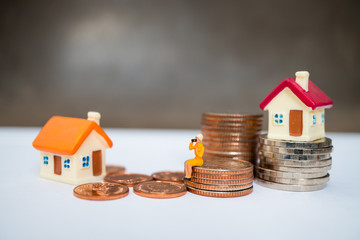 Miniature people, woman sitting on stack coins and mini house using as business and property concept