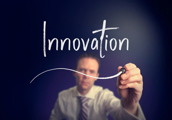 A businessman writing a innovation concept with a white pen on a clear screen.