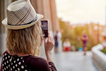 Female traveler in sunhat is taking a photo of using mobile phone.