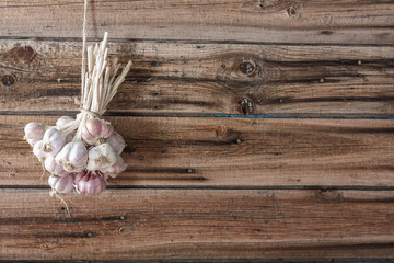 Bundles of fresh garlic dried on vintage wooden wall © Loraliu
