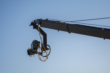 4K cinema production camera with crane in the blue sky. mass movie industrial.