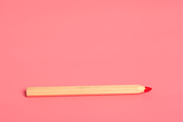 Red pencil on pink background close up